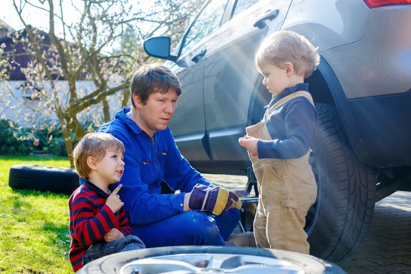 小さな子供の男の子と彼の父親は車のホイールを変更します — ストック写真