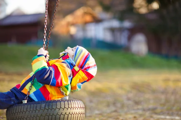 Beetje kid jongen swingen op speelplaats buiten — Stockfoto