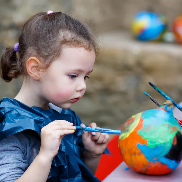 Petite fille enfant peinture avec des couleurs sur citrouille — Photo