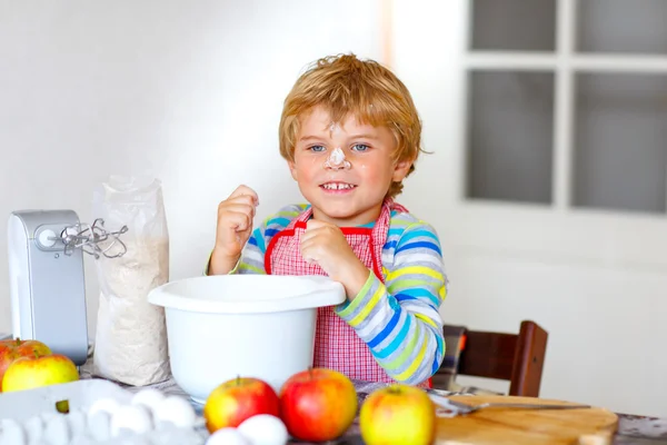 Divertido chico rubio hornear pastel de manzana en el interior — Foto de Stock