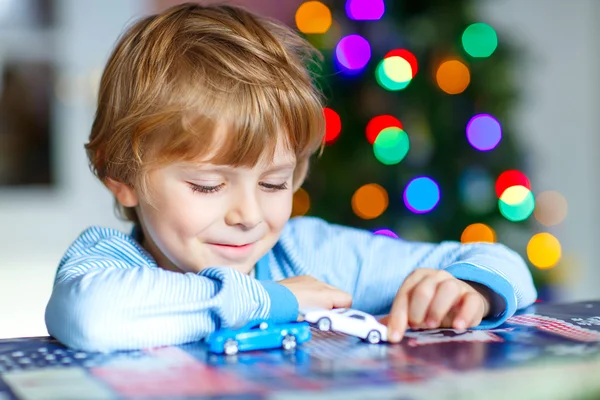 Маленький блондин играет с автомобилями и игрушками дома — стоковое фото
