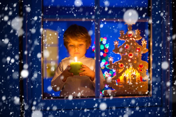 Μικρό αγόρι παιδί στέκεται από παράθυρο στο χρόνο Χριστουγέννων και κρατώντας — Φωτογραφία Αρχείου