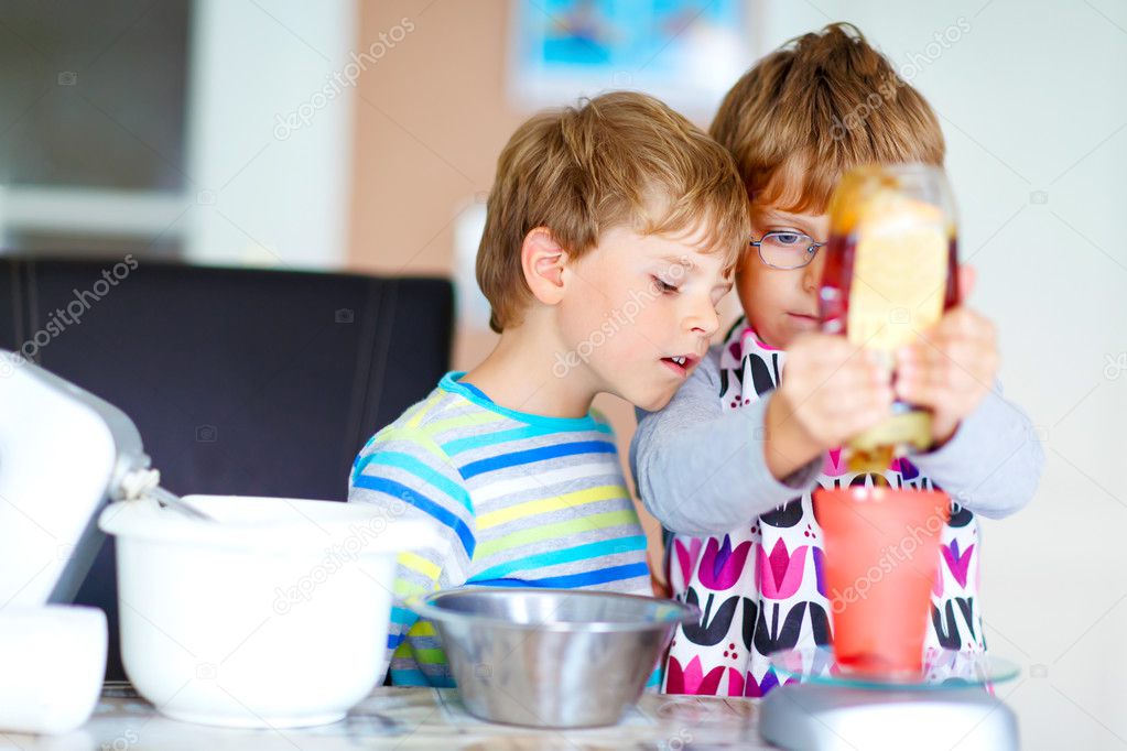 Two kid boys baking cake in domestic kitchen