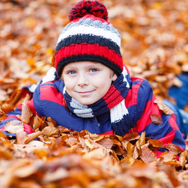 Sonbahar yaprakları arasında küçük şirin bir çocuk parkta..