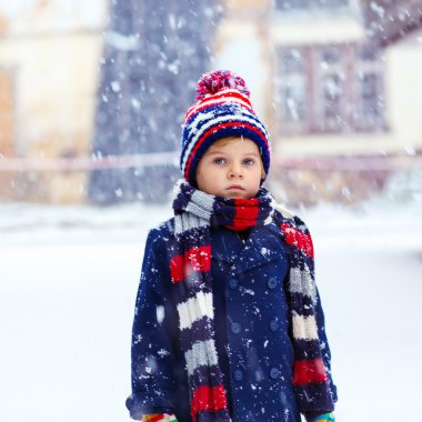 Mutlu çocuk kışın karla eğleniyor.