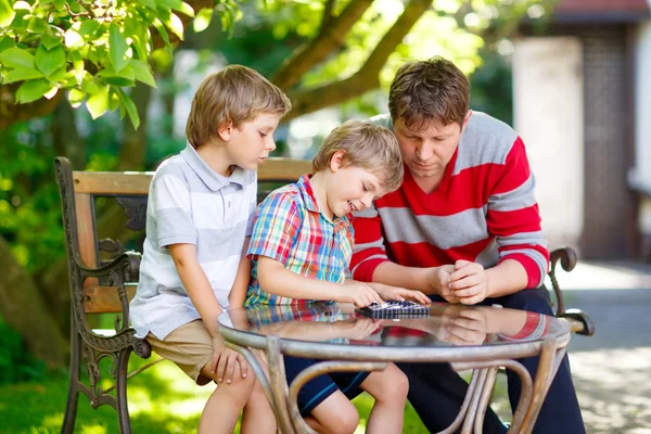 Two little kid boys and father playing together checkers game — Stock Photo, Image