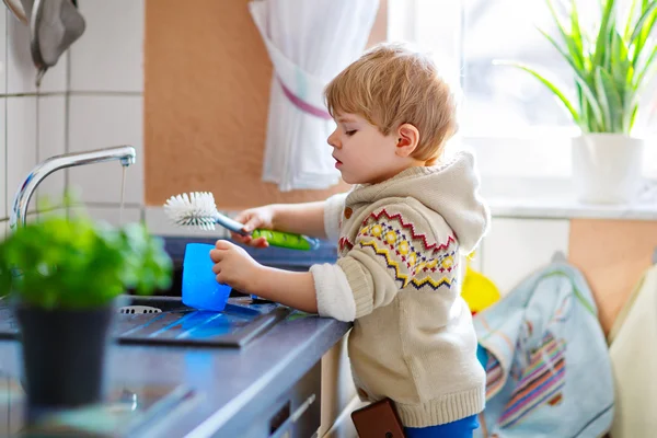 Pequeño niño ayudando en la cocina con lavar los platos — Foto de Stock