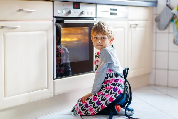 Смешной блондин мальчик печет кексы в помещении — стоковое фото