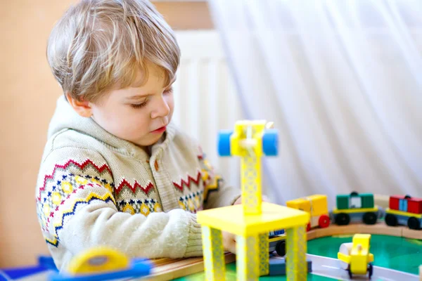 Menino pequeno brincando com ferrovia de madeira, dentro de casa — Fotografia de Stock