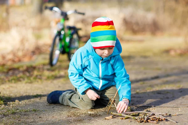 Söt liten pojke leker med trä pinnar i stadsparken, utomhus — Stockfoto