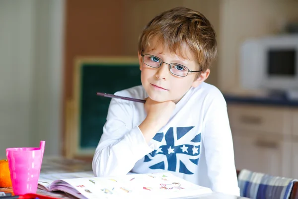 Menino da escola feliz com óculos em casa fazendo lição de casa — Fotografia de Stock