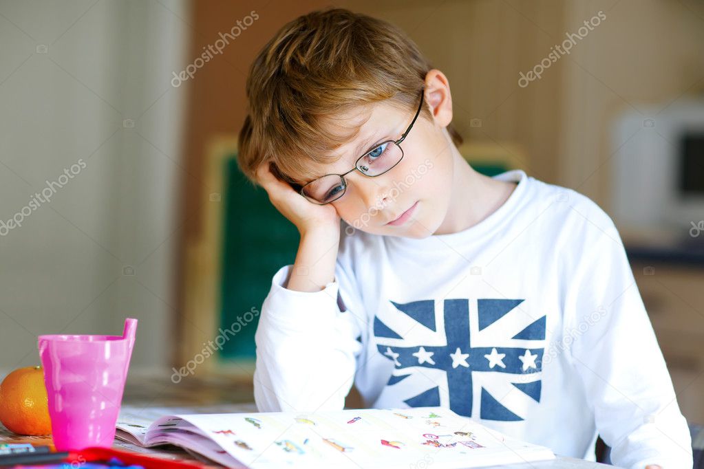 Frustrated kid boy with glasses at home making homework