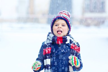 Mutlu çocuk kışın karla eğleniyor.