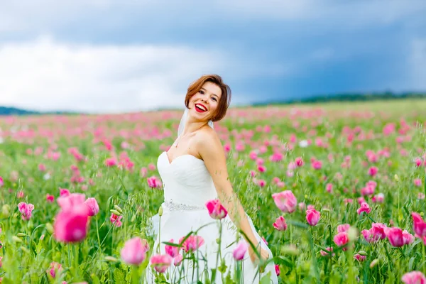 Boldog menyasszony, fehér ruhában, szórakozás a mák virág mező — Stock Fotó