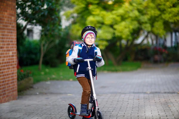Kasklı küçük çocuk şehirde scooterıyla geziyor. — Stok fotoğraf