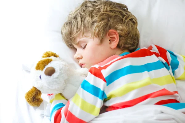 Маленький блондин мальчик в разноцветной ночной одежде спит — стоковое фото