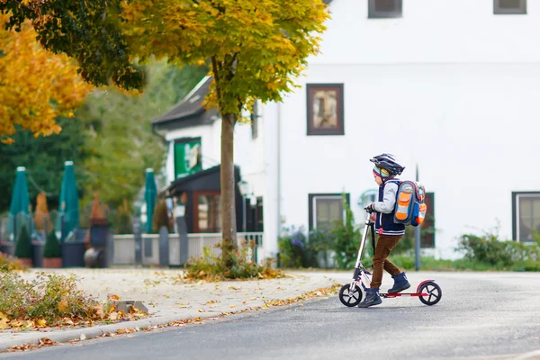 Kleiner Junge mit Helm fährt mit seinem Roller durch die Stadt — Stockfoto