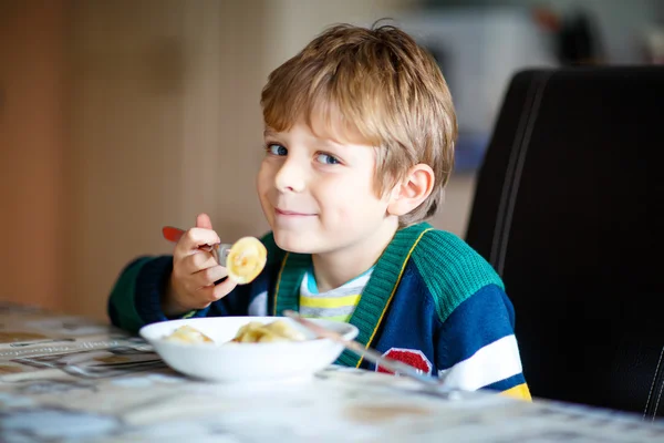 Liten skola pojke äter pasta inomhus i en personalmatsal. — Stockfoto