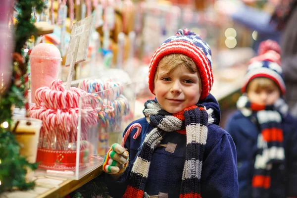 Malé dítě chlapec s cukrové třtiny stojí na vánoční trh — Stock fotografie