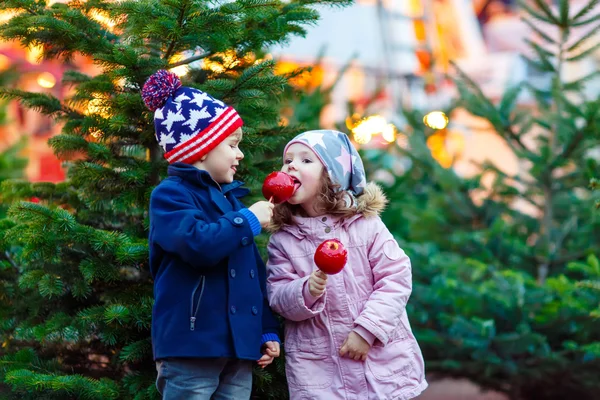 Dvě malý děti jíst vykrystalizoval apple na vánoční trh — Stock fotografie