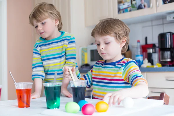 Två små blonda barn pojkar färgning ägg till påsk — Stockfoto