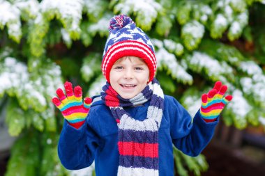 Mutlu çocuk kışın karla eğleniyor.