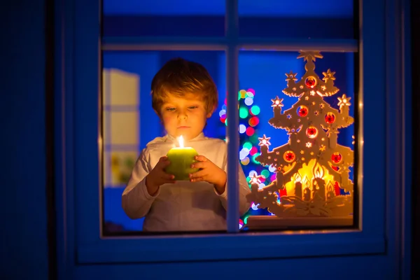 Kleine jongen jongen permanent door raam kerst tijd ingedrukt te houden — Stockfoto