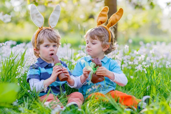 Двое маленьких детей играют с пасхальным шоколадным кроликом — стоковое фото