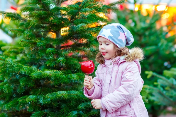 Linda niña comiendo azúcar manzana en el mercado de Navidad — Foto de Stock