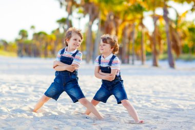 İki küçük çocuk tropik sahilde eğleniyor.