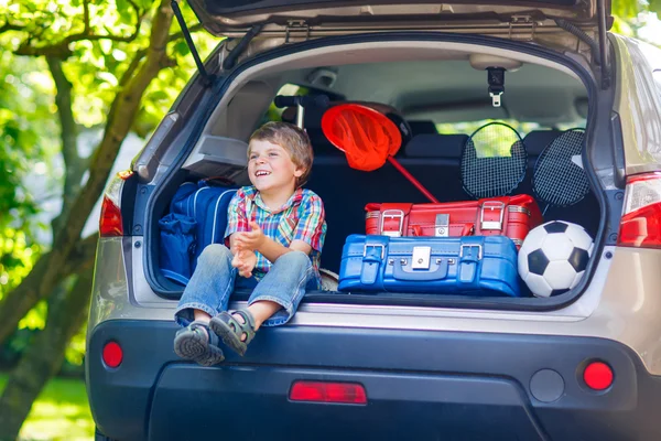 Kleine jongen jongen zitten in auto kofferbak net voor vertrek voor vaca — Stockfoto