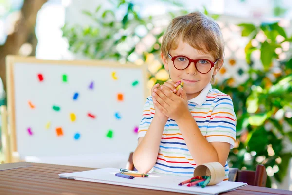 Kleine school jongen jongen met bril holding bijenwasstiftjes — Stockfoto