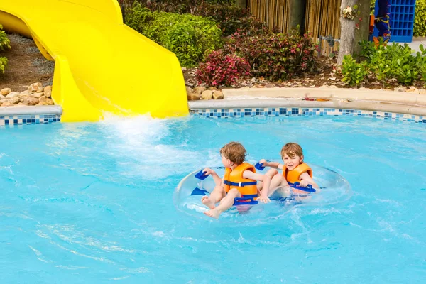 Excited children in water park riding on slide with float — Stock Photo, Image