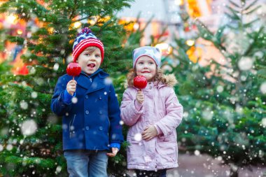 İki küçük çocuk Noel piyasasında yeme şeker elma