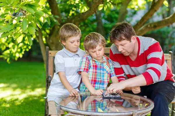 Due bambini piccoli ragazzi e padre che giocano insieme a dama — Foto Stock