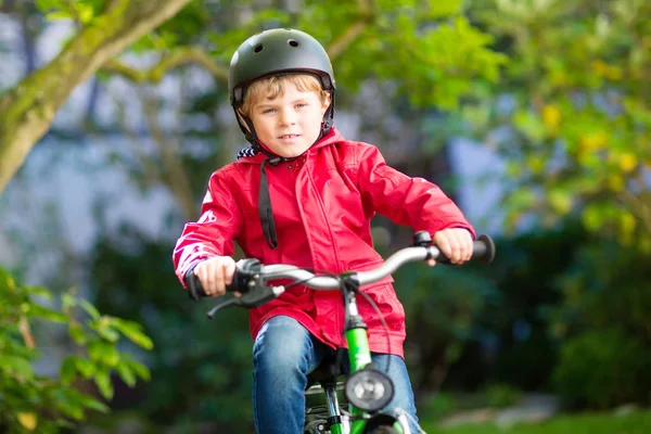 Beetje kid jongen in helm rijden met zijn fiets in de stad — Stockfoto
