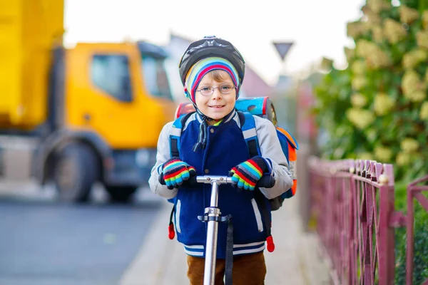 Petit garçon en casque chevauchant avec son scooter dans la ville — Photo