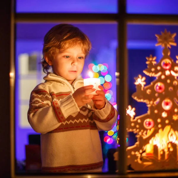 Malý chlapec dítě stojící u okna v době Vánoc a držení — Stock fotografie