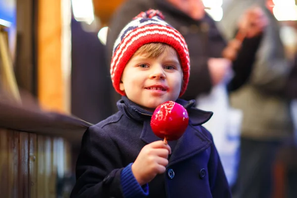 Bambino piccolo ragazzo mangiare dolce mela sul mercato di Natale — Foto Stock