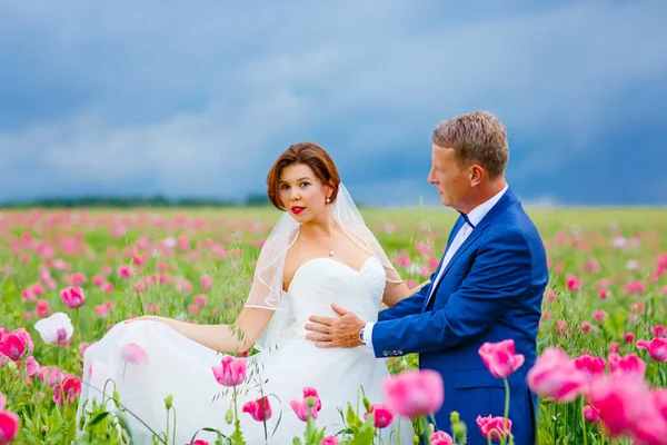 Happy wedding couple in pink poppy field — Stock Photo, Image