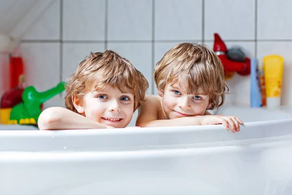 Two little kids boys playing together in bathtub — Stock Photo, Image