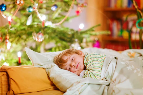 Kleiner süßer Junge schläft unter dem Weihnachtsbaum — Stockfoto