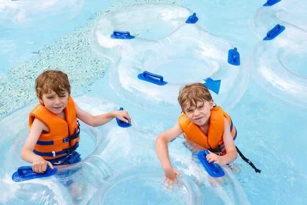 Bambini entusiasti nel parco acquatico cavalcando sullo scivolo con galleggiante — Foto Stock