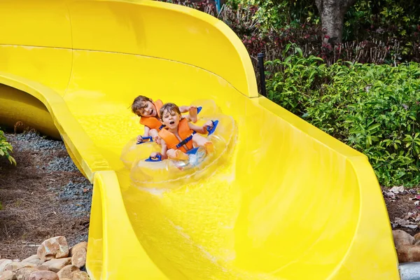 Podekscytowany dzieci w parku wodnym, jazda na slajd z float — Zdjęcie stockowe