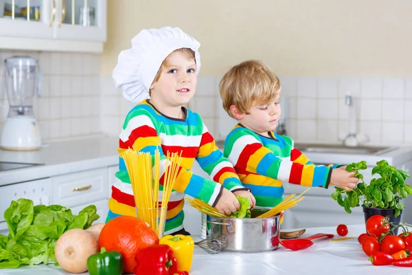 Two little kid boys cooking pasta with vegetables — Stock Photo, Image