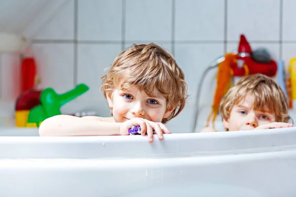 Two little kids boys playing together in bathtub — Stock Photo, Image