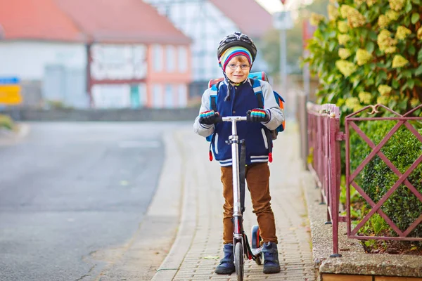 小さな男の子でヘルメットに乗って彼のスクーターで街で — ストック写真