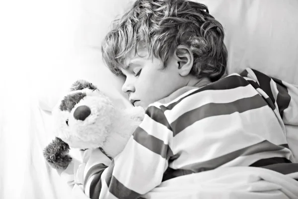 Piccolo ragazzo biondo in abiti da notte colorati dormire — Foto Stock