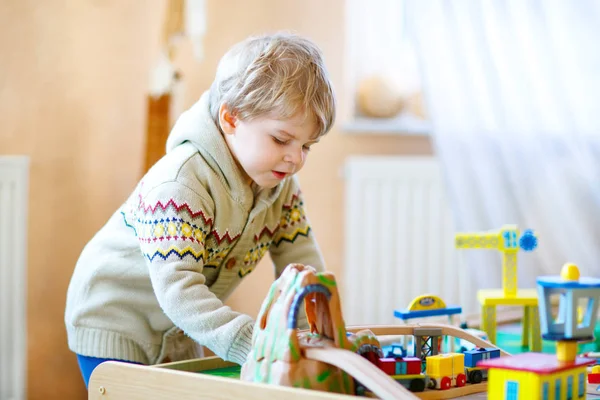 Малыш играет с деревянной железной дорогой, в помещении — стоковое фото