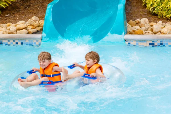 Bambini entusiasti nel parco acquatico cavalcando sullo scivolo con galleggiante — Foto Stock